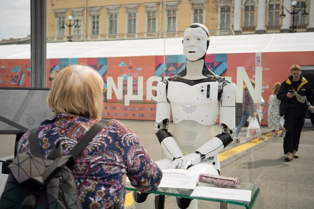 На Книжном салоне на Дворцовой площади проходит перформанс: робота поместили в прозрачный куб, посетители могут зайти внутрь и провести с ним «короткий допрос».