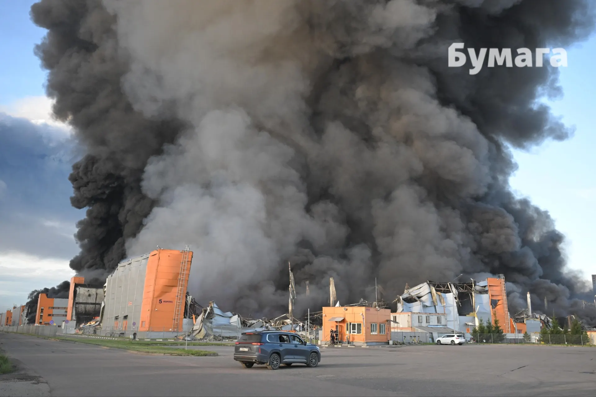 В складском комплексе «Уткина Заводь» горят корпуса 3, 4 и 5 — корпуса 4 и 5 выгорели почти полностью; у корпуса 3 заметна пожарная машина.