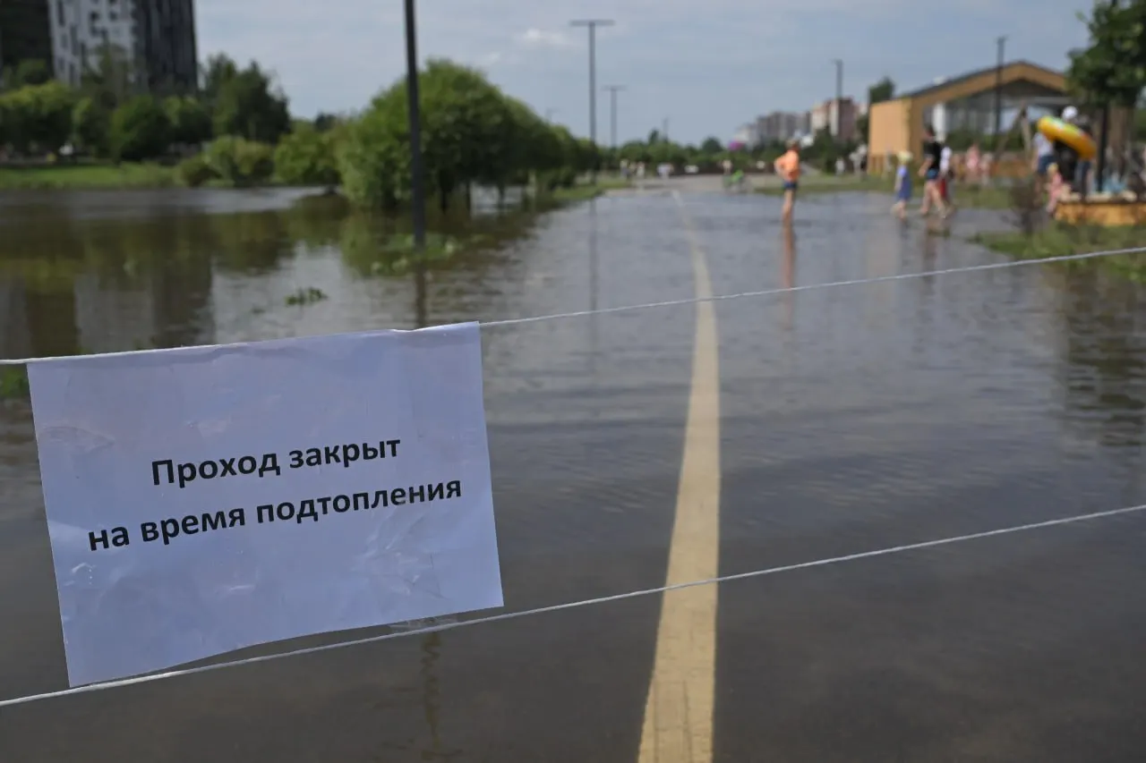 В Кудрове у затопленного участка парка натянули верёвки с табличкой «Проход закрыт», но местные жители продолжают ходить по луже. Власти заявляют, что вода уходит и зеленые насаждения не пострадают.