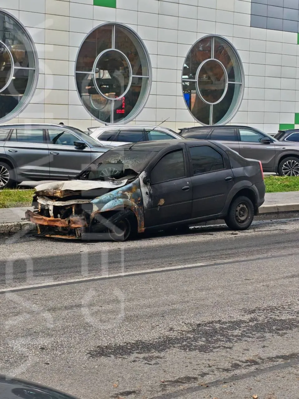 На участке дороги близ Мурманска обнаружен сгоревший автомобиль Logan и мусор; местные жители требуют привести территорию в порядок.